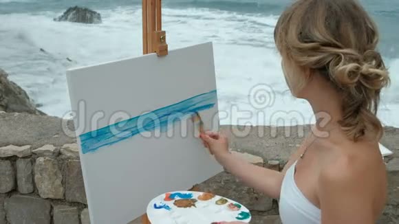 年轻的艺术家在浪涛拍岸写海景视频的预览图