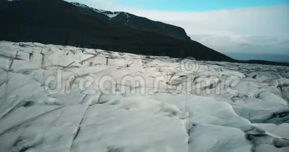 鸟瞰冰谷冰川瓦特纳火山带黑色火山灰直升机飞过冰岛的冰山视频的预览图
