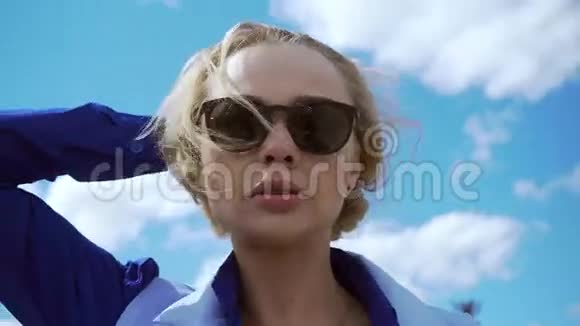 美丽迷人的金发女郎穿着白色连衣裙戴着阳光照射下的飞行员太阳镜视频的预览图