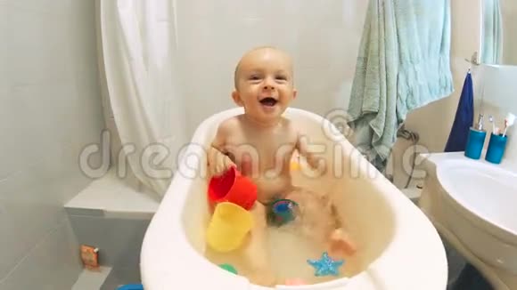 快乐快乐的小男孩在小塑料浴缸里飞溅视频的预览图