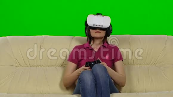 女士在VR眼镜玩游戏时坐在沙发在家里绿色屏幕视频的预览图