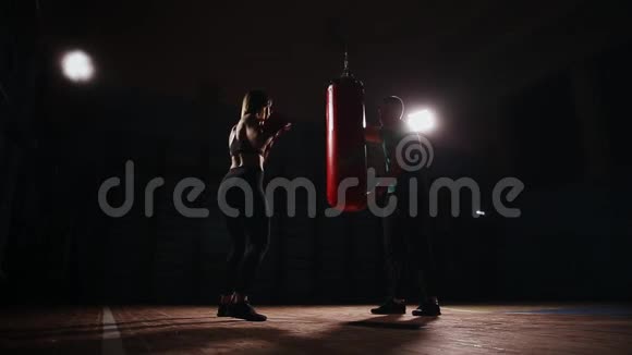 年轻漂亮的黑发女人穿着运动服和他的拳击教练一起训练手拿拳击手套视频的预览图
