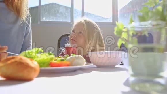 小金发女孩坐在餐桌旁喝果汁吃早餐视频的预览图