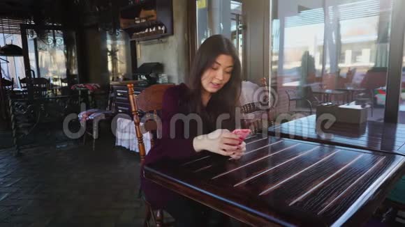 年轻女性老师用智能手机在咖啡馆检查测试视频的预览图