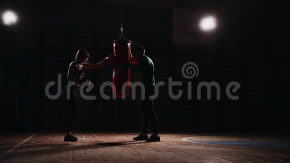 年轻漂亮的黑发女人穿着运动服和他的拳击教练一起训练手拿拳击手套视频的预览图