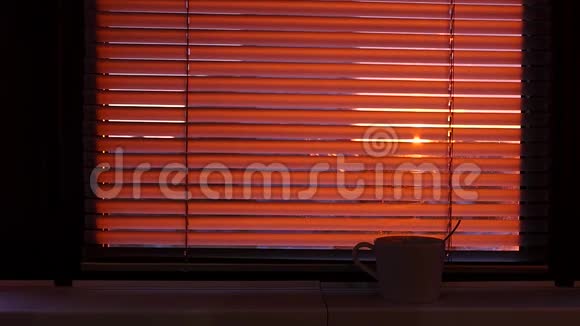窗台上有一杯热茶或咖啡在紧闭的贾洛西后面你可以看到城市和夕阳视频的预览图