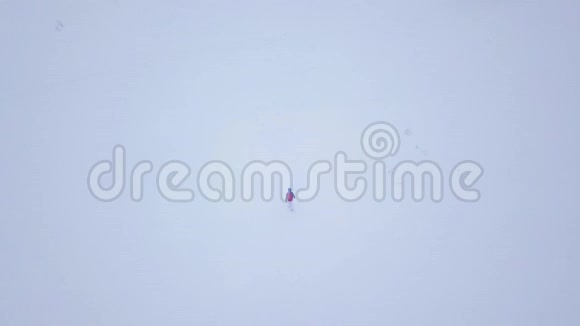 飞越孤独的旅游女孩沿着一座覆盖着雪的山顶行走雪霜天气视频的预览图