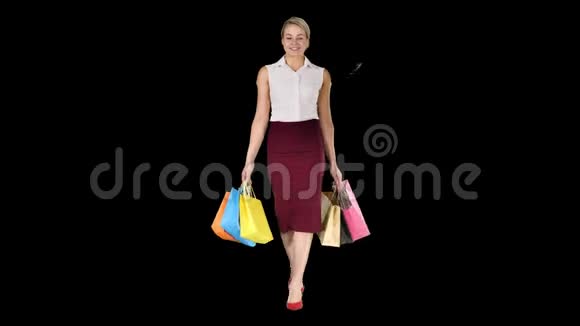 快乐的女人拿着购物袋微笑着走路阿尔法频道视频的预览图