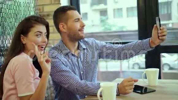 可爱夫妇在使用手机自拍时玩得开心和鬼脸的肖像两个快乐的年轻人视频的预览图