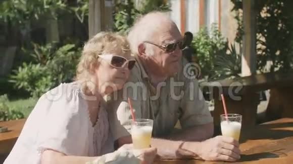 一对老年夫妇坐在户外咖啡馆喝着鸡尾酒视频的预览图