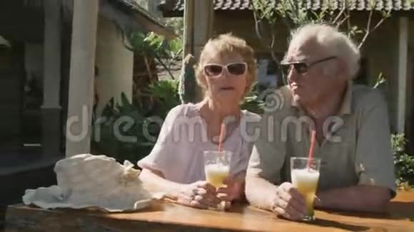 一对老年夫妇坐在户外咖啡馆喝着鸡尾酒视频的预览图