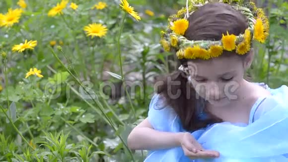 穿着春天花圈的小女孩坐在草地上视频的预览图