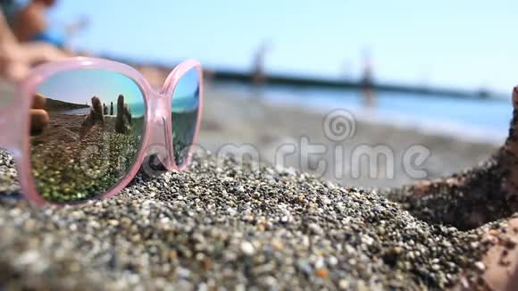 太阳镜在沙滩上海滩上与休息的人在眼镜上反映粉色眼镜视频的预览图