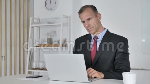 沉思的中年商人思考与笔记本电脑工作视频的预览图