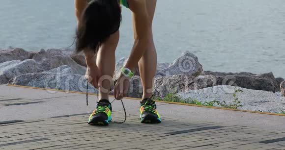 健康的生活方式健身女跑步者在阳光明媚的海边跑步前系鞋带视频的预览图