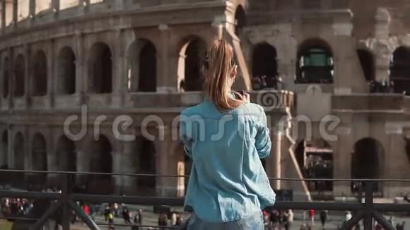 旅游妇女用她的智能手机在意大利罗马拍摄竞技场和君士坦丁拱门的照片慢动作视频的预览图