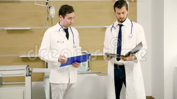 两名医生在医院的病房里谈话手里拿着文件夹视频的预览图