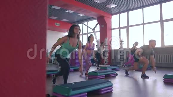 步健美操运动课一群人与教练一起在步进器上锻炼视频的预览图