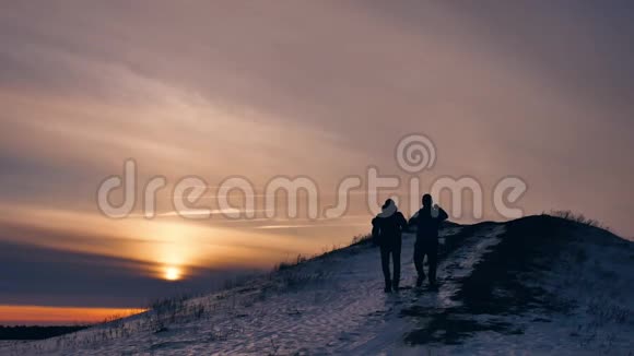人冬天剪影做自拍拍照欢乐雪阳光一群游客走在夕阳的上方视频的预览图
