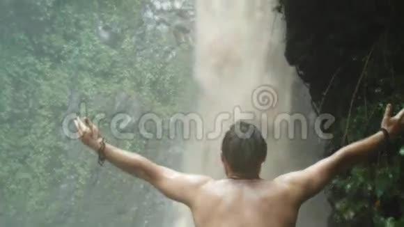 一个人站在瀑布旁双臂张开视频的预览图