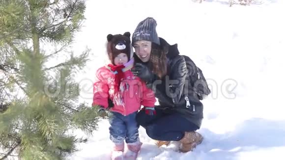 年轻的母亲和小女儿在雪地森林里玩耍视频的预览图