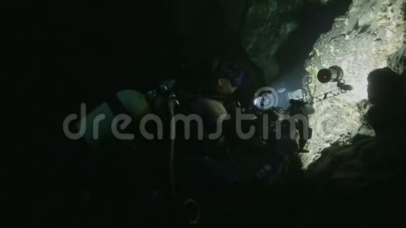 两名潜水员在古巴塞诺特的石墙附近拍摄视频的预览图
