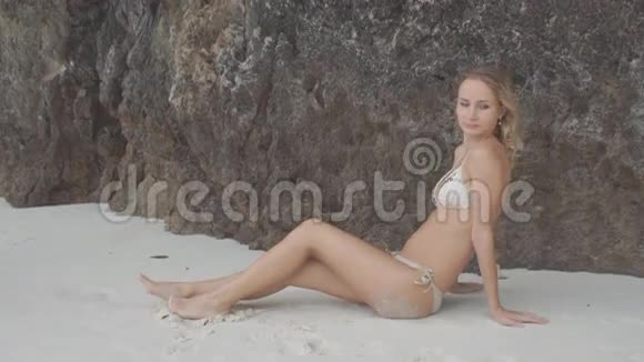 美丽的女人穿着泳衣在海滩上的岩石背景视频的预览图