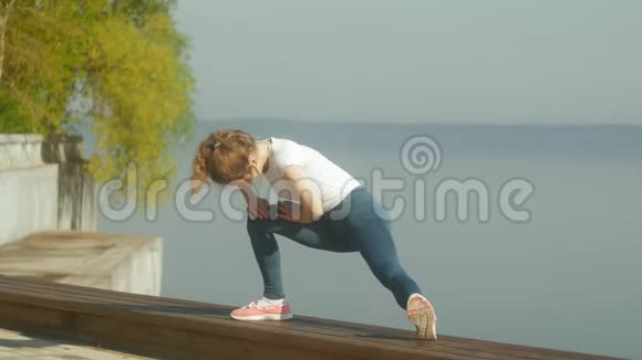 年轻的健身妇女在河边的户外健身房锻炼视频的预览图