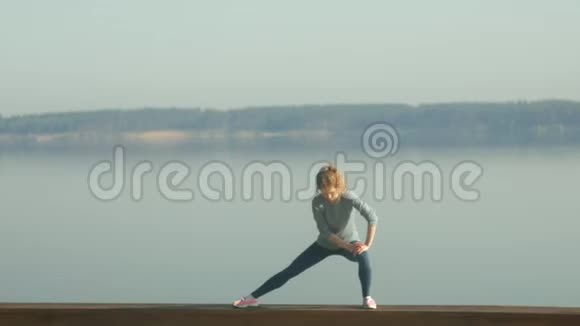 年轻的健身妇女在河边的户外健身房锻炼视频的预览图