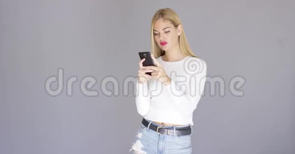 时髦的金发女郎在检查她的手机视频的预览图