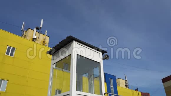 在黄蓝相间的建筑物和天空背景上装有扬声器的小屋视频的预览图