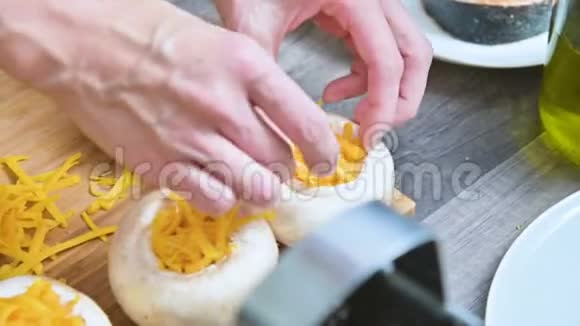 女性手的特写用酱油和磨碎的奶酪填充新鲜的豪奇尼蘑菇筹备工作视频的预览图