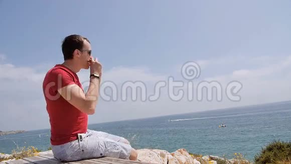 年轻人坐在悬崖边上吃三明治视频的预览图