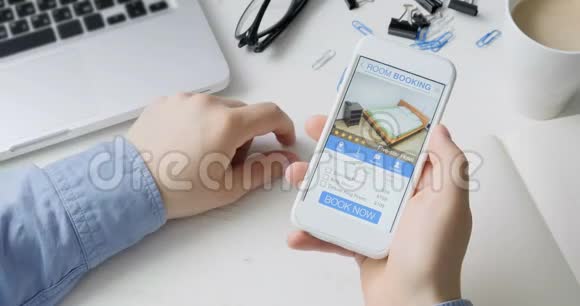 男人在公寓里用智能手机预订房间在线预订手机应用程序坐在他的办公桌前视频的预览图