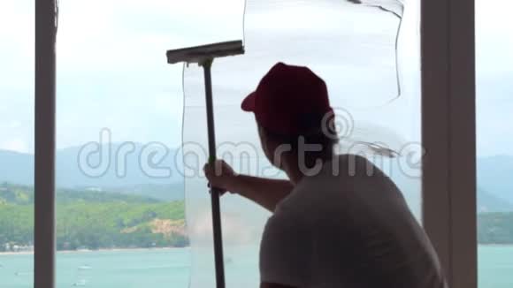 清洁员工使用刮刀清洁窗户玻璃与全景海景视频的预览图