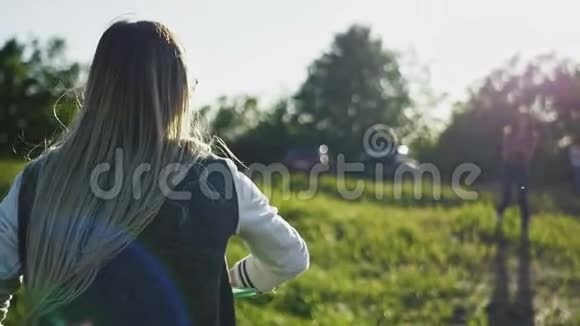 年轻的健身女性穿着蓝色牛仔裤和白色运动鞋在夏天在高山的草地上捕捉飞盘视频的预览图