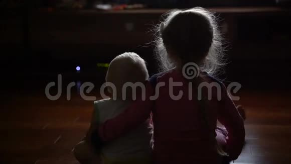 弟弟和妹妹坐在黑暗中看电视视频的预览图