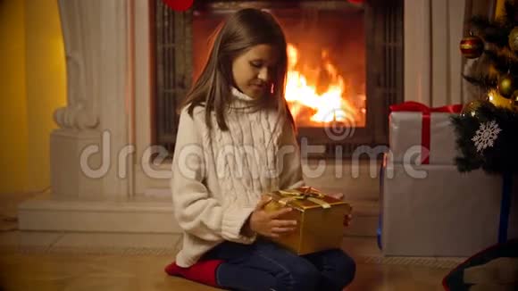 可爱的女孩穿着毛衣打开神奇的圣诞礼盒光和火花从盒子里飞出视频的预览图