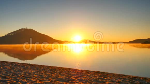 太阳眼镜和深色帽子的高个子男人正在日落时在海滩上奔跑运动积极分子在湖边奔跑的剪影视频的预览图