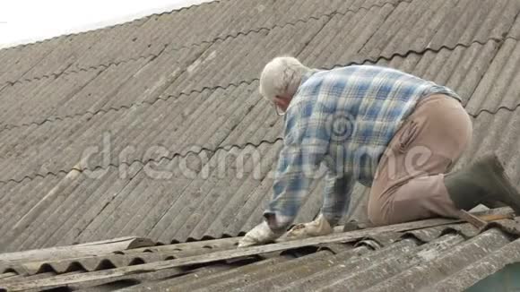 一位老人正在自己修屋顶石板上的旧木屋视频的预览图