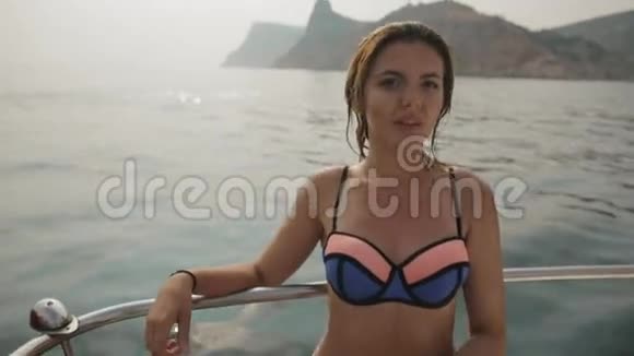 迷人的年轻女子穿着比基尼湿发坐在海上游艇上视频的预览图