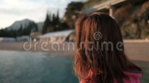 年轻的黑发女子站在湖边看日落视频的预览图