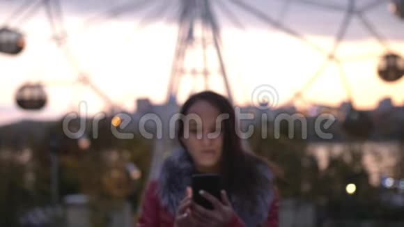 美丽的深色头发的年轻女子在夜城的街道上散步时使用手机灯光很亮很慢视频的预览图