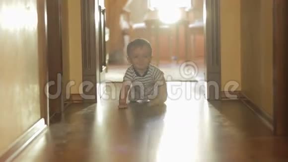 可爱活泼的幼儿男孩在木地板上朝镜头爬行视频的预览图