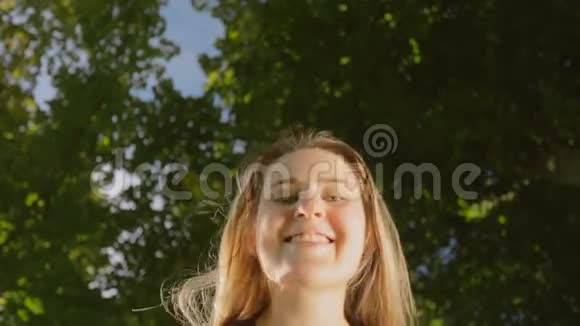 美丽的金发女人弯下腰在公园的镜头里微笑视频的预览图