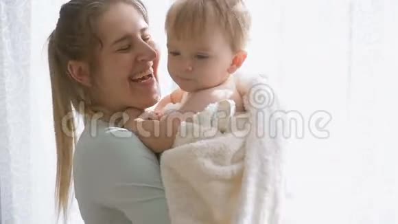慢动作特写镜头快乐微笑的母亲在卧室的窗口拥抱她的小儿子视频的预览图