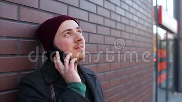 那个孤独的年轻人在城市的砖墙附近打电话视频的预览图
