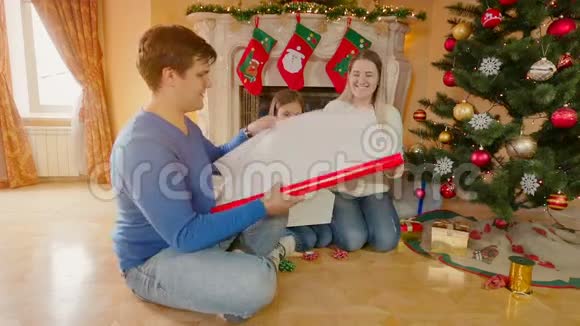 幸福的家庭女孩用红色包装纸包装圣诞礼物视频的预览图