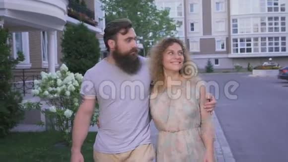 那个留着胡子的家伙和他的女朋友一个金发女郎走在城市的人行道上视频的预览图