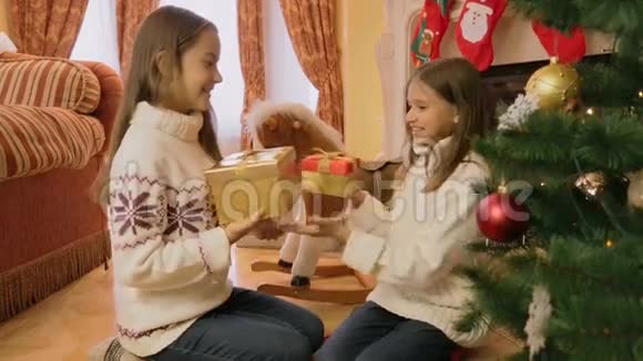 两个快乐的女孩互相赠送圣诞礼物并打开它们视频的预览图